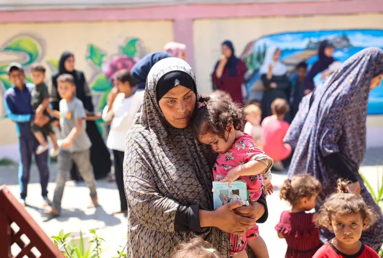 Mãe com filho ao colo na Faixa de Gaza
