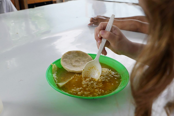 Criança saboreia refeição à base de peixe em Macholoa, Honduras